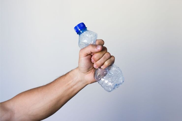Schiacciare bottiglietta plastica con la mano